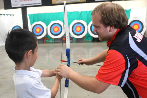 Child and instructor at free archery activity at the Washington State Fair
