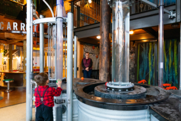 A child explores at Hands On Children’s Museum in Olympia, surrounded by water play and treehouse structures.