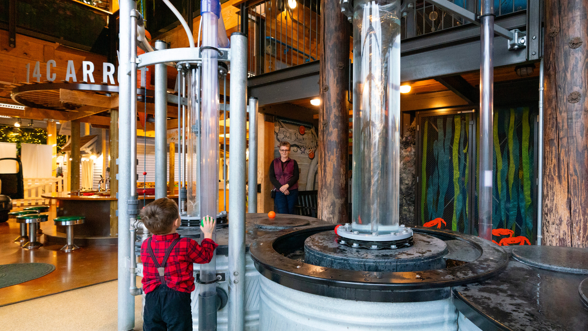 A child explores at Hands On Children’s Museum in Olympia, surrounded by water play and treehouse structures.