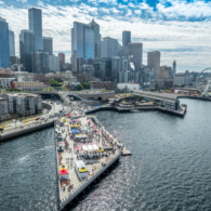 Aerial view of Seattle’s new 20-acre Waterfront Park filled with families enjoying the sunny grand opening celebration.