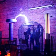 A live coil demonstration inside the SPARK Museum of Electrical Invention in Bellingham, surrounded by glowing electrical displays.