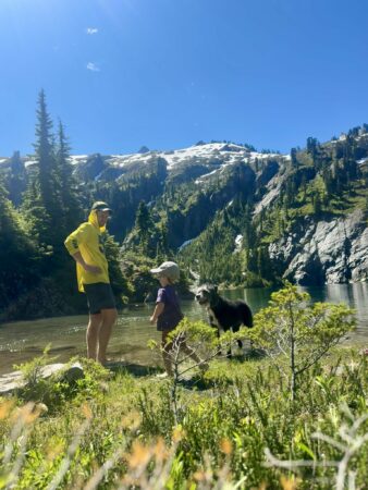 Parent, child, and dog relaxing at an alpine lake in the North Cascades