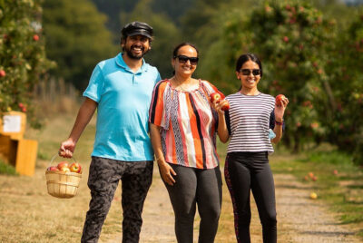 Family holding up apples they picked at Bellewood Acres orchard