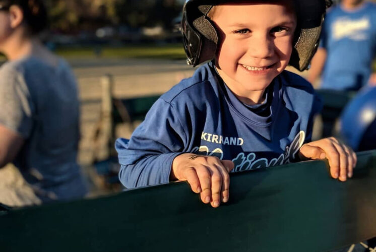 Young child smiling in a baseball uniform before a game.