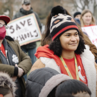 Parents, teachers and community members gather at a South Seattle Schools Fundraising Alliance event, holding signs in support of saving and investing in local schools.