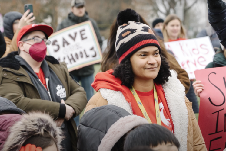 Parents, teachers and community members gather at a South Seattle Schools Fundraising Alliance event, holding signs in support of saving and investing in local schools.