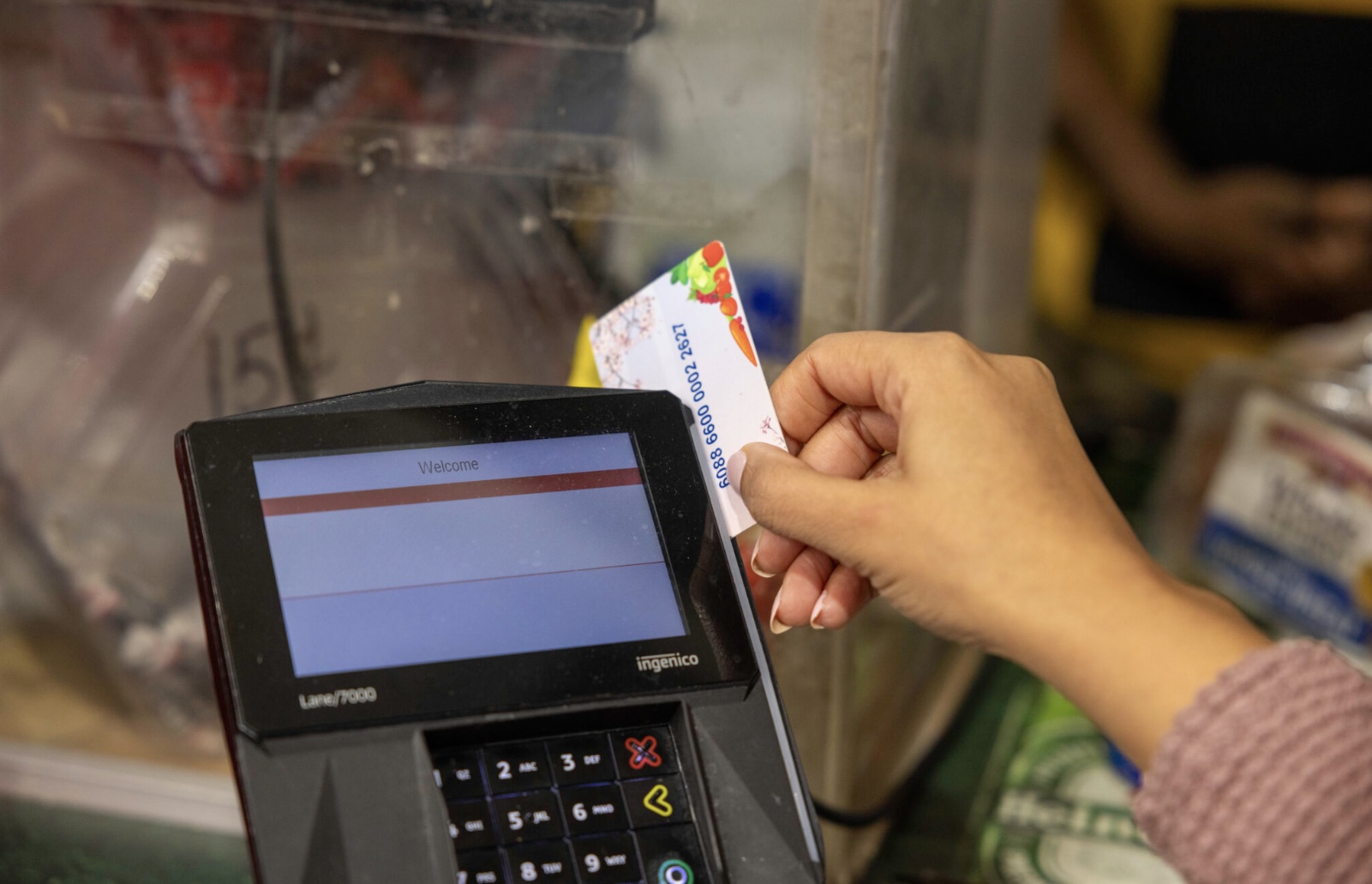 Washington shopper checking out at grocery store; many families rely on SNAP and state food assistance benefits.