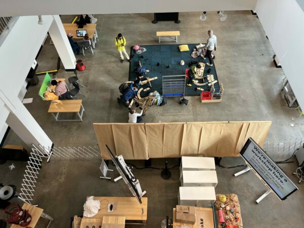 Overhead view of the Pacific Science Center’s Maker and Innovation Lab, with kids and families working on hands-on STEM projects at colorful tables.