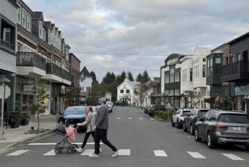 Seabrook’s town center on the Washington coast, showing pastel-colored shops, restaurants, and pedestrians walking along the main street on a sunny day.
