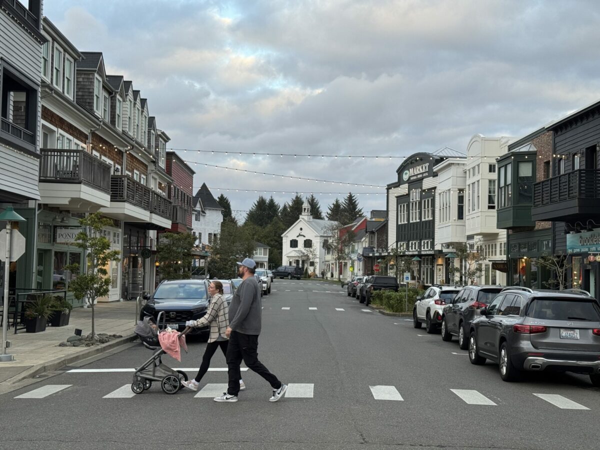 Seabrook’s town center on the Washington coast, showing pastel-colored shops, restaurants, and pedestrians walking along the main street on a sunny day.