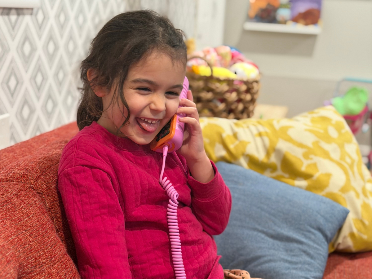 Child using a screen-free phone for kids in a playroom while learning phone etiquette at home